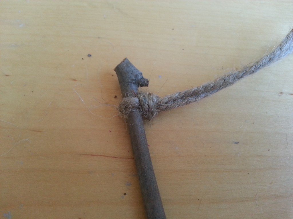 Make a simple knot around the stick with both pieces of jute. Make a simple knot around the stick with both pieces of jute.