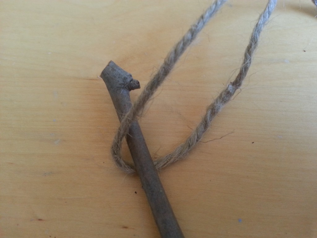 Place the first stick in the middle of a length of cut jute. Place the first stick in the middle of a length of cut jute.