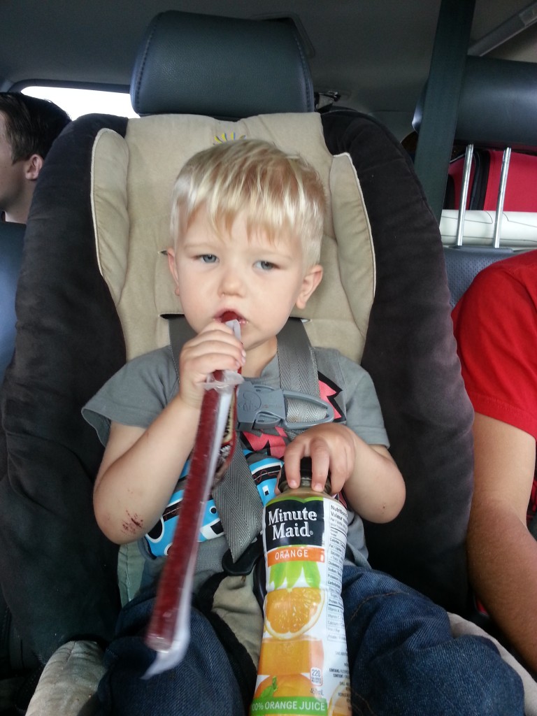 Scrappy boy eating his road trip meat snacks and orange juice.